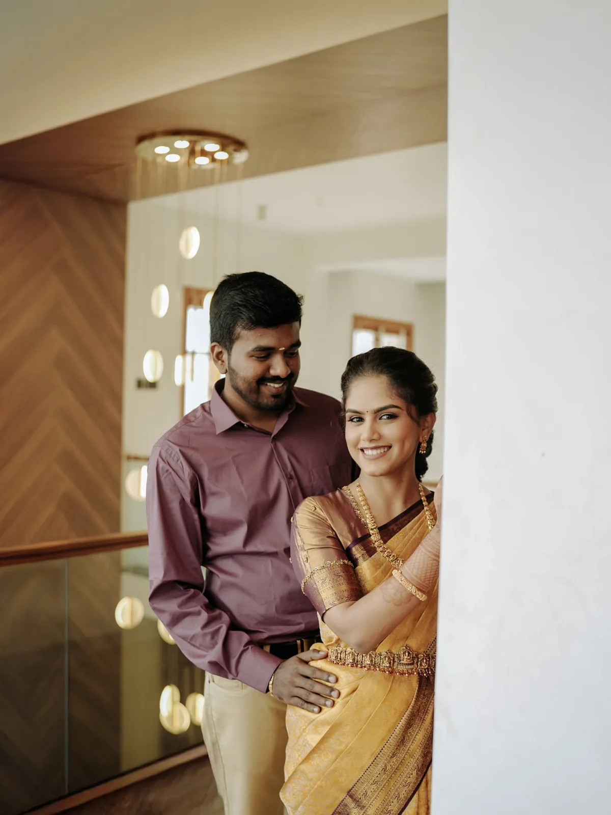 The couple by a pillar, the bride smiling at the camera